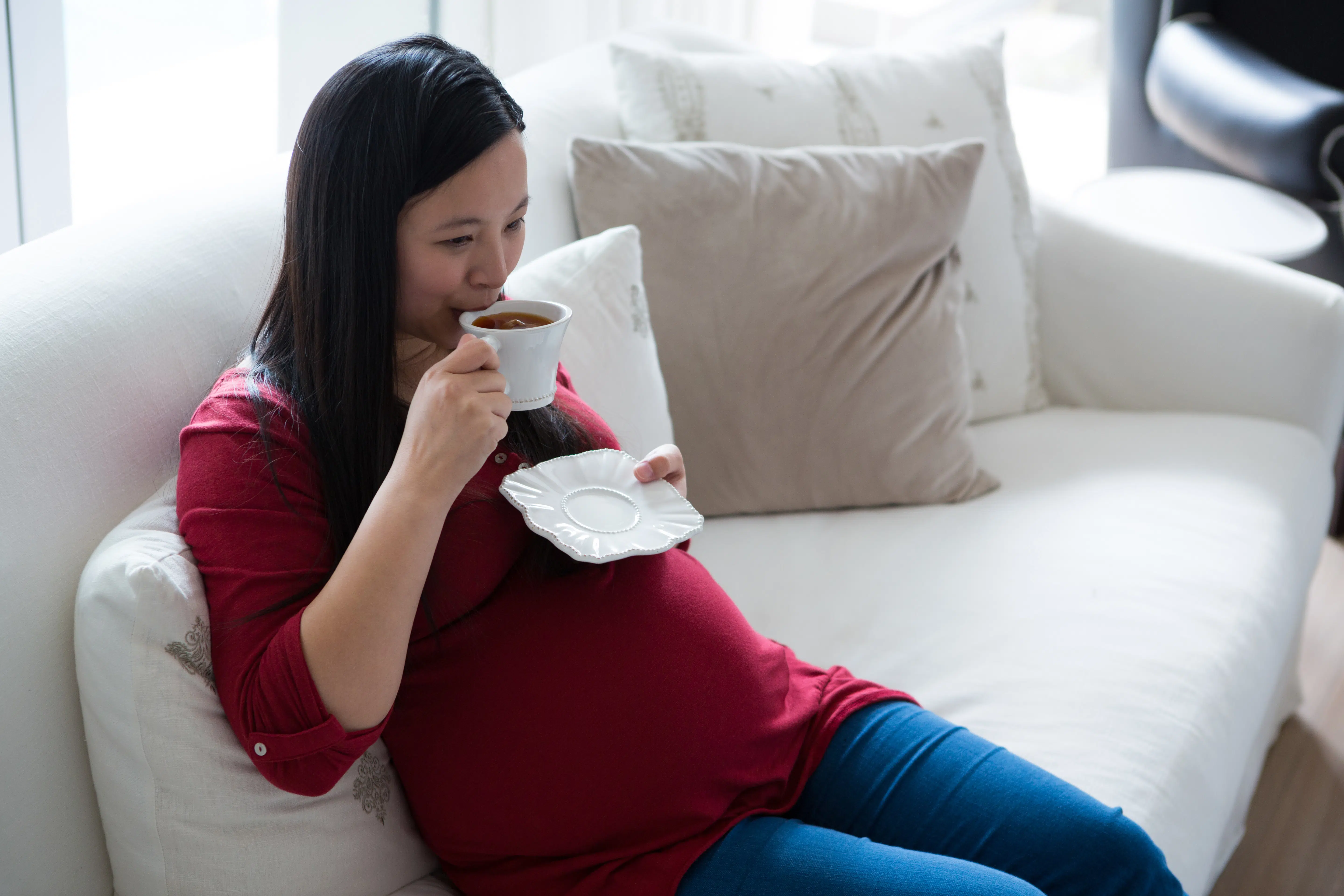 pregnant woman having coffee in living room