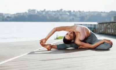 human body flexibility. young woman does exercises against lake