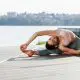 human body flexibility. young woman does exercises against lake